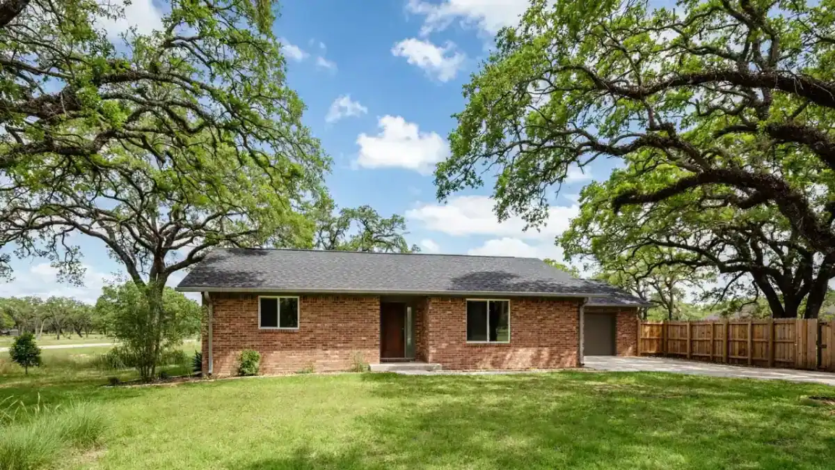 Restored brick home with new shingles, clean brick and a green lawn under a blue sky